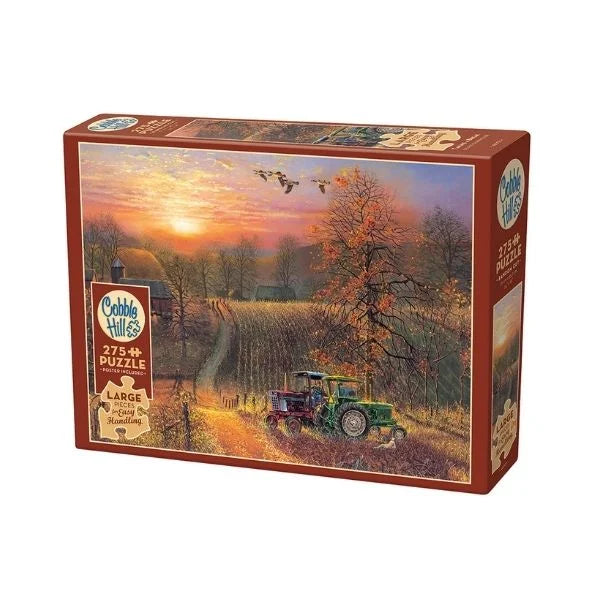 Jigsaw puzzle box with a scenic design of a sunset over a field and tractor, featuring the Cobbles Hill brand.