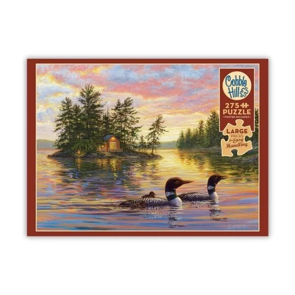Cobble Hill puzzle featuring a scenic illustration of two loons on a lake at sunset.